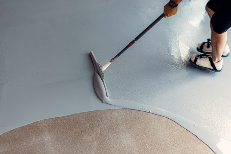 A construction worker apply grey epoxy resin in an industrial hall