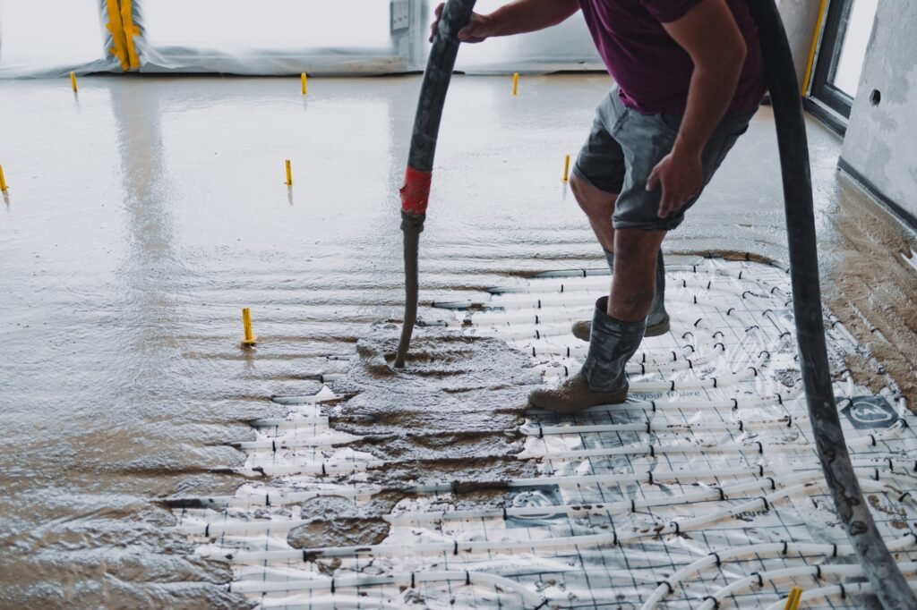 Construction worker pouring concrete on radiant floor heating system