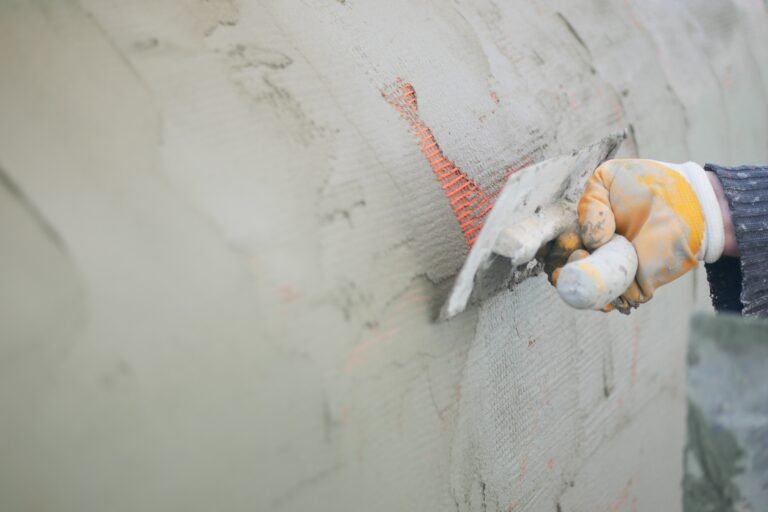 Construction worker applying plaster to wall surface in progress