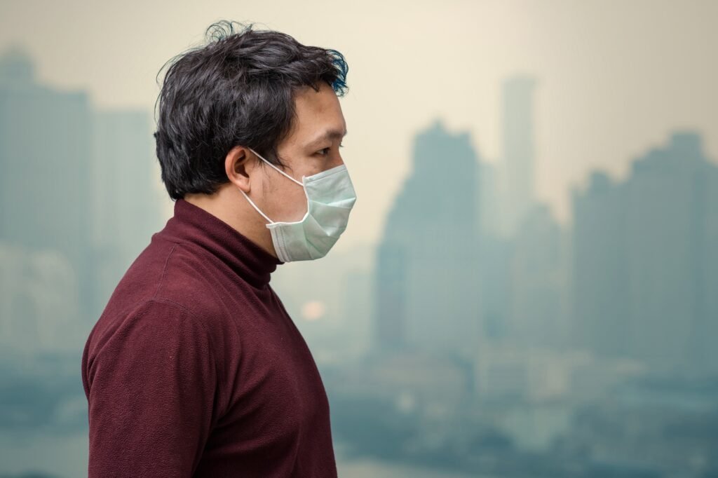 Asian man wearing the face mask against air pollution at the balcony of High Apartment