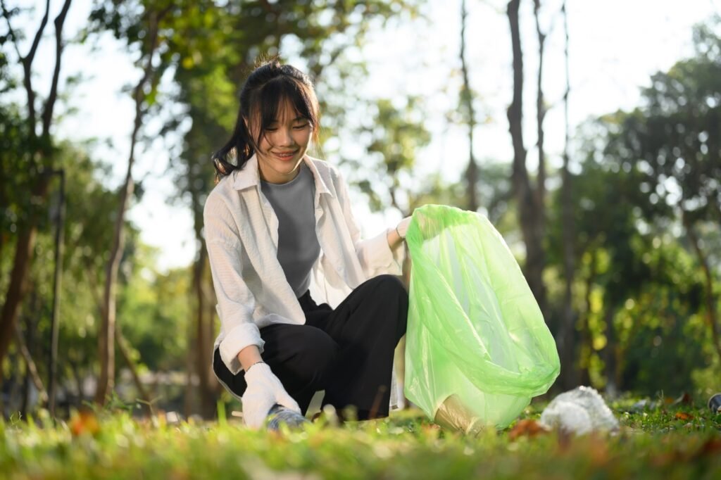 Beautiful young woman with garbage bags cleaning up public park. Environmental protection concept
