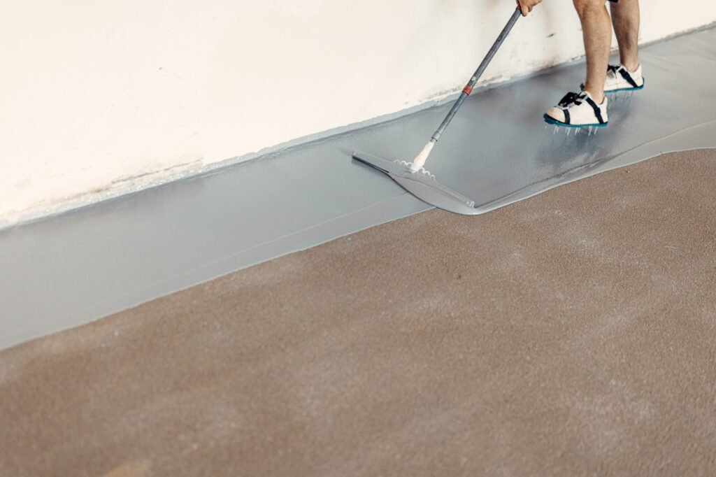 Construction worker applying epoxy resin on concrete floor