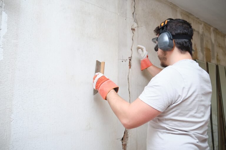 Construction worker repairing a crack on wall