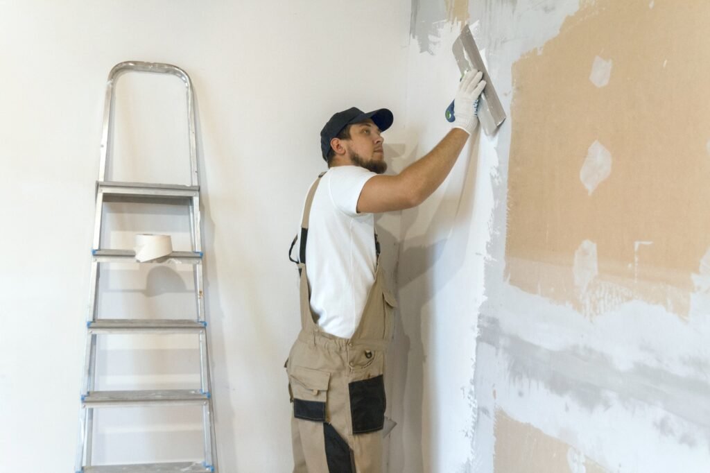 Male painter with a putty knife in his hands repairing the wall