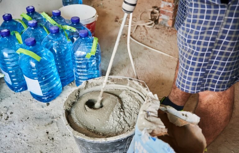 Male worker using electric concrete mixer at construction site.