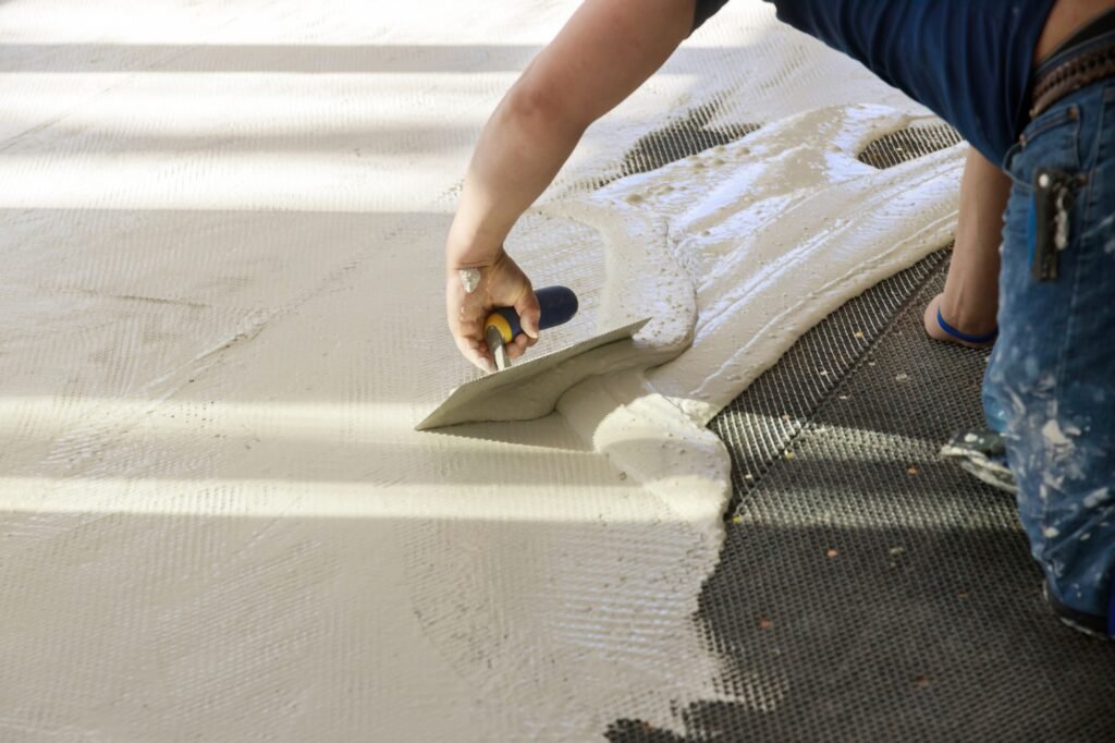 Professional worker troweling mortar concrete in preparation for laying for tiler on the floor.