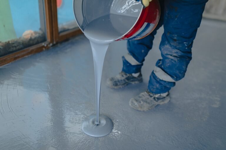 The worker applies gray epoxy resin to the new floor