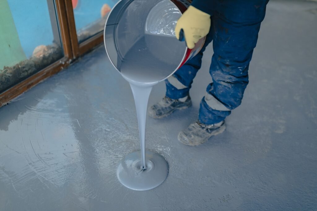 The worker applies gray epoxy resin to the new floor