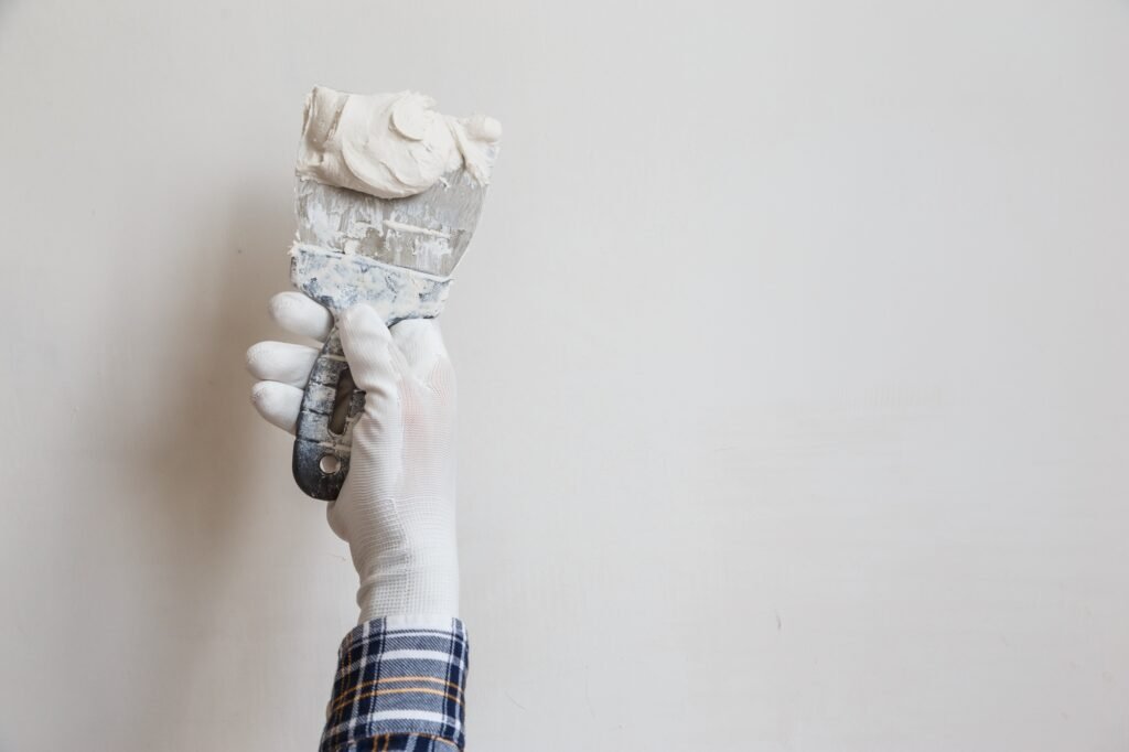 Worker in white gloves performs plastering of the walls of the room