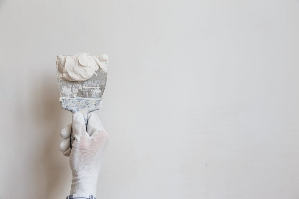 Worker in white gloves performs gypsum plastering of the walls of the room