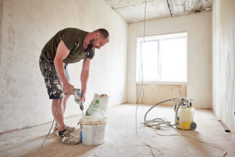Worker mixing dry mortar with handheld mixer in bucket
