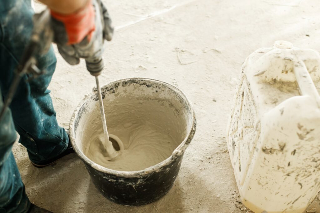 Worker mixing gypsum plaster with water for plastering walls